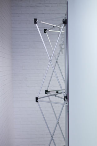 Foldable aluminum frame pop-up display, leaning against a white brick wall, advertising technology Chemnitz