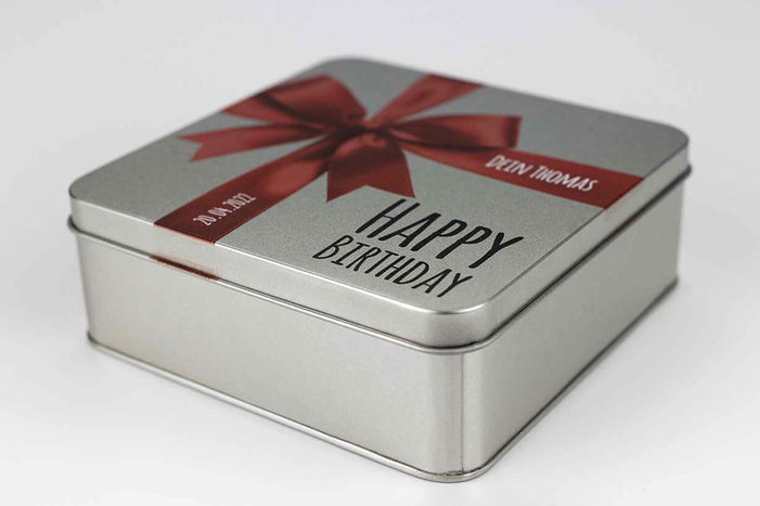 eine weißblechdose mit einer roten schleife und einem schriftzug happy birthday bedruckt
