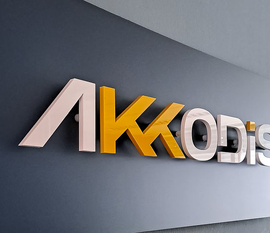 Graue Wand mit Akkodis 3D Acrylschriftzug in gelb weiß glänzend