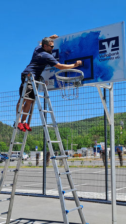 Mann installiert Werbetechnik-Aufkleber am Basketballkorb