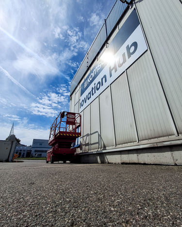Red scissor lift truck in front of the Innovation Hub building, sunny day.