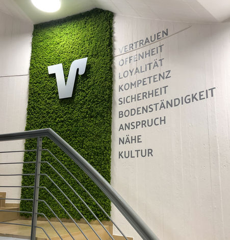 Green moss wall with a silver V logo and nine company values displayed on the wall. Moss picture.