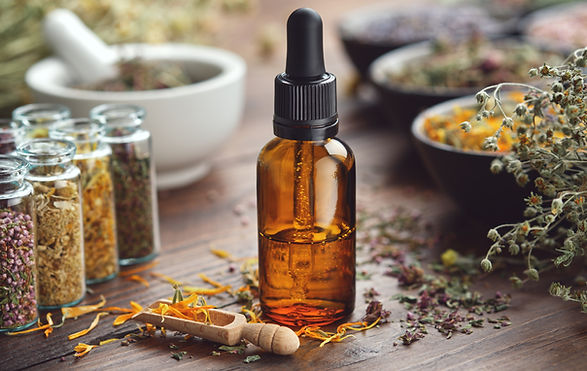 Dropper bottle of essential oil. Glass bottles of medicinal herbs. Mortar and bowls of dry