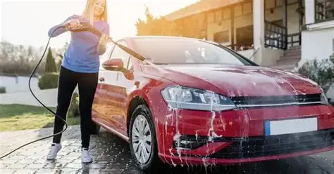 Mulher com lavadora de alta preção lavando um carro.