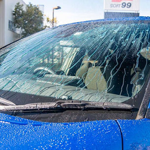 Para-brisa de carro azul repelindo água numa lavagem
