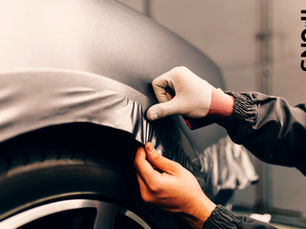Pessoa realizando processo de envelopamento, mãos aplicam película cinza em um carro preto na oficina; texto lateral SNAIL CAR DETAIL, clima profissional e cuidadoso