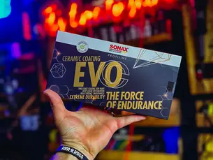 Mão de profissional da estética automotiva segurando a embalagem do SONAX Ceramic Coating CC Evo, destacando produto premium de proteção cerâmica com durabilidade de até 5 anos.