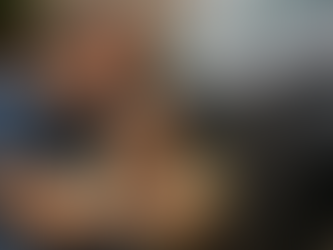 Pessoa lavando carro em casa com esponja de cozinha amarela e observando riscos na lataria com expressão de preocupação.