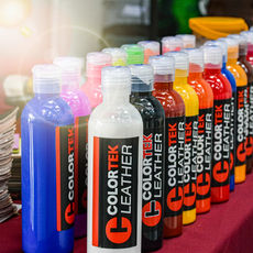 Tintas para couro Colortek à base de água, organizadas por cor sobre o balcão, mostrando variedade de tonalidades para personalização automotiva.