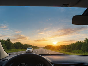 Visão do motorista através do para-brisa ao entardecer, mostrando estrada reta, céu alaranjado, carro vindo na direção oposta e interior do veículo, destacando clareza e redução de reflexos