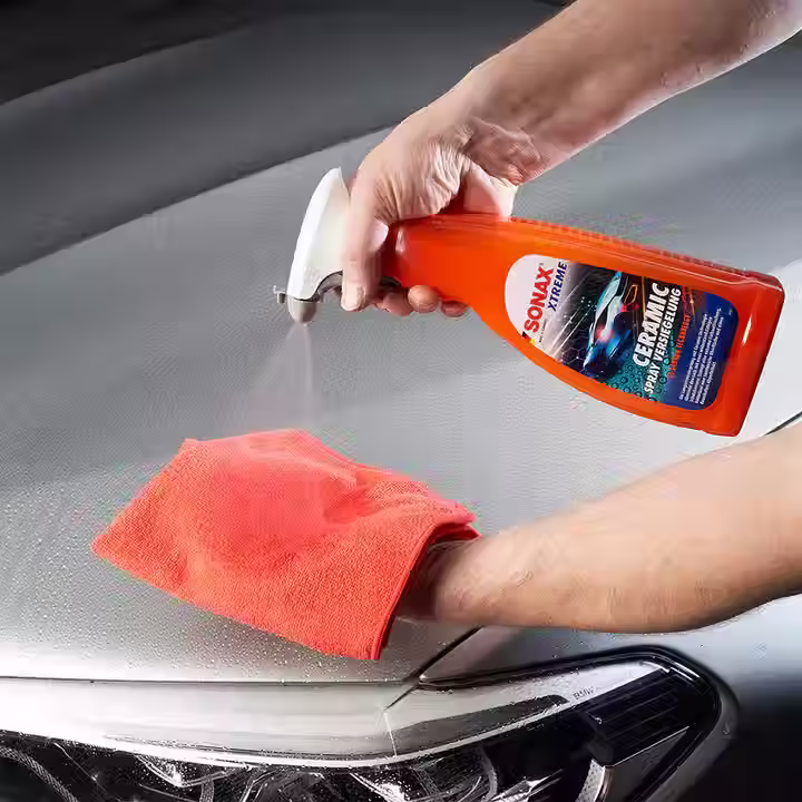 Aplicação de Selante de pintura em um pano microfibra, ao fundo capo de carro com gotas e hidro repelência  