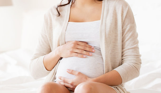 A surrogate holding her pregnant belly.