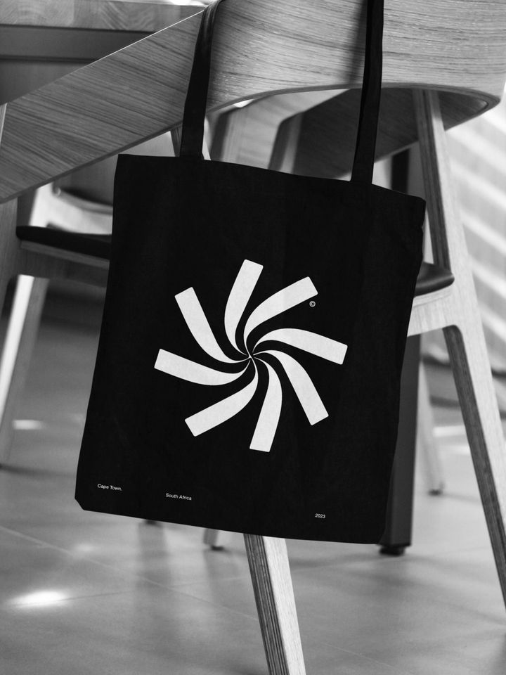 Minimal brand mark on canvas bag over wooden chair — premium visual identity for design studios