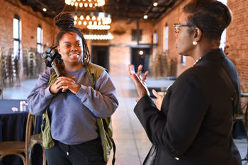 Photographer capturing video while another attendee speaks at Entrefest