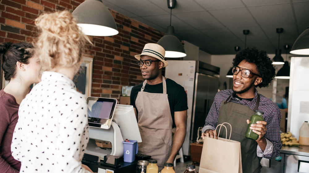 Two men in cafe serving two female customers