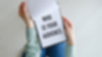 Who is Your Audience text on blank business card being held by a woman's hand with blurred