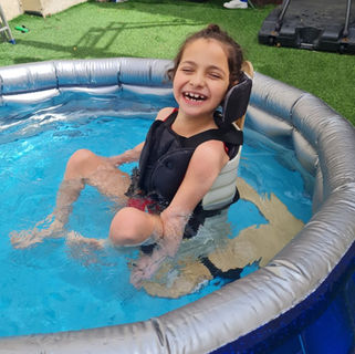 Smiling girl sitting in a portable Testa-Seat during a family outing, showing inclusive seating on the go.