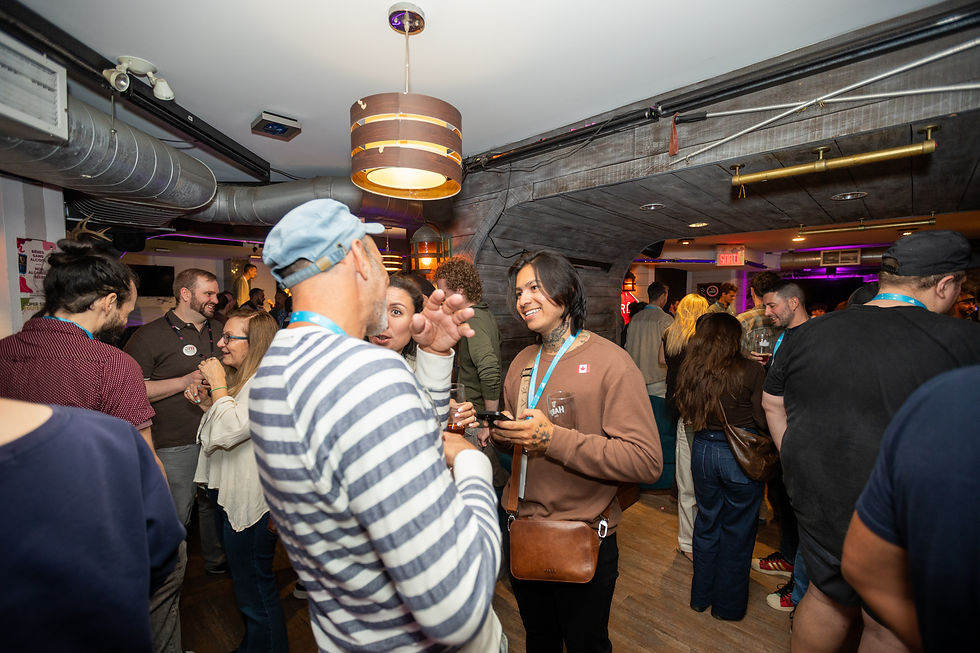 Crowded bar party with people chatting and holding drinks under warm lights; neon SORTIE sign glows in the background.