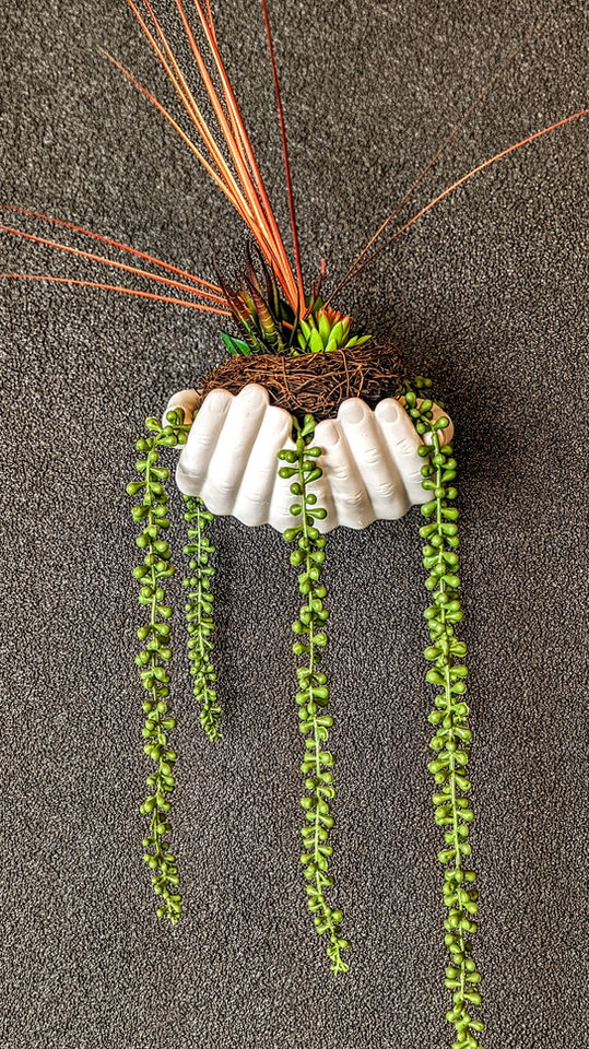 Plaster hands holding a birds nest.