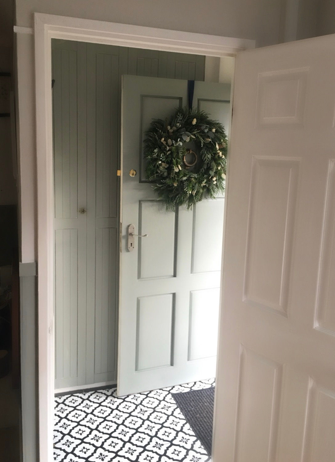 Green front door in paint shade ‘pigeon’ with black and white stick-on fooor tiles aka floor pops