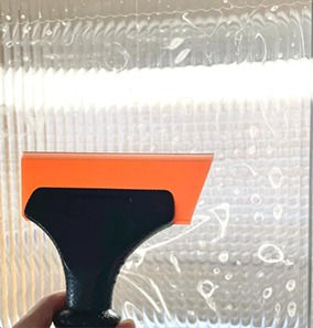 smoothing out air bubbles from reeded glass film with squeegee