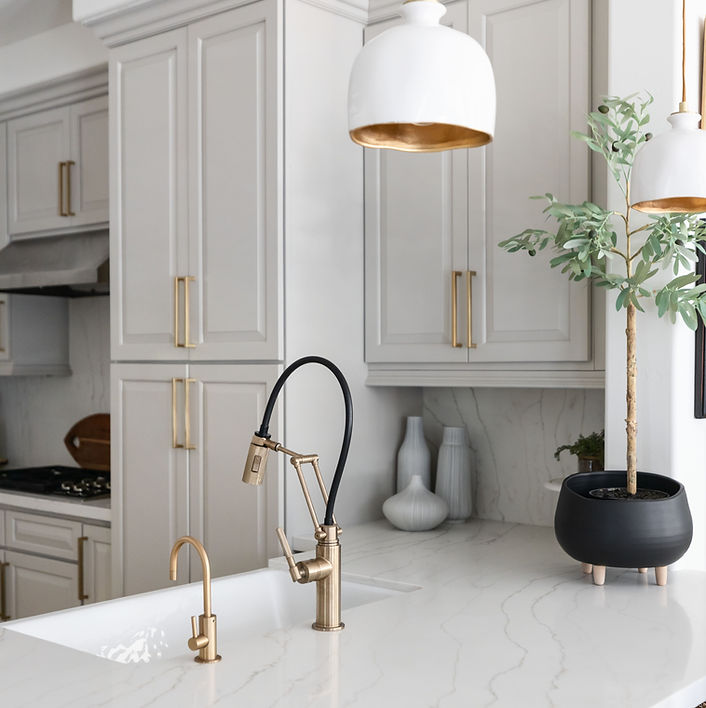 Kitchen design. White and gold pendant hanging over a quartz countertop with a white ceramic sink.