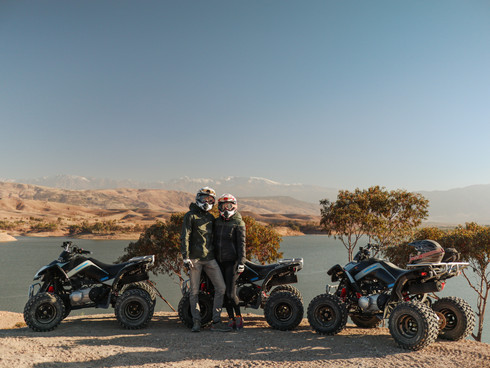 Twee personen en quads in de woestijn met uitzicht op een meer en de bergen