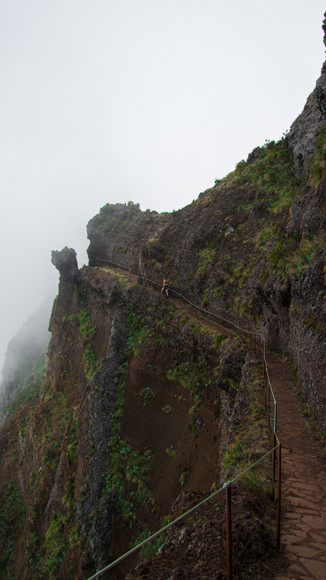 Wandelaar op een pad langs een bergklif in de mist