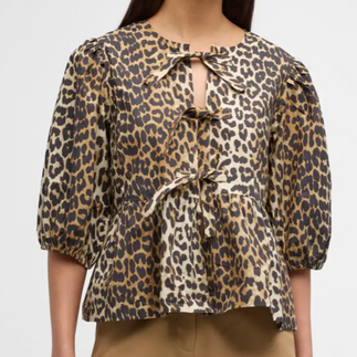 A close up of a model wearing a cheetah print tied blouse
