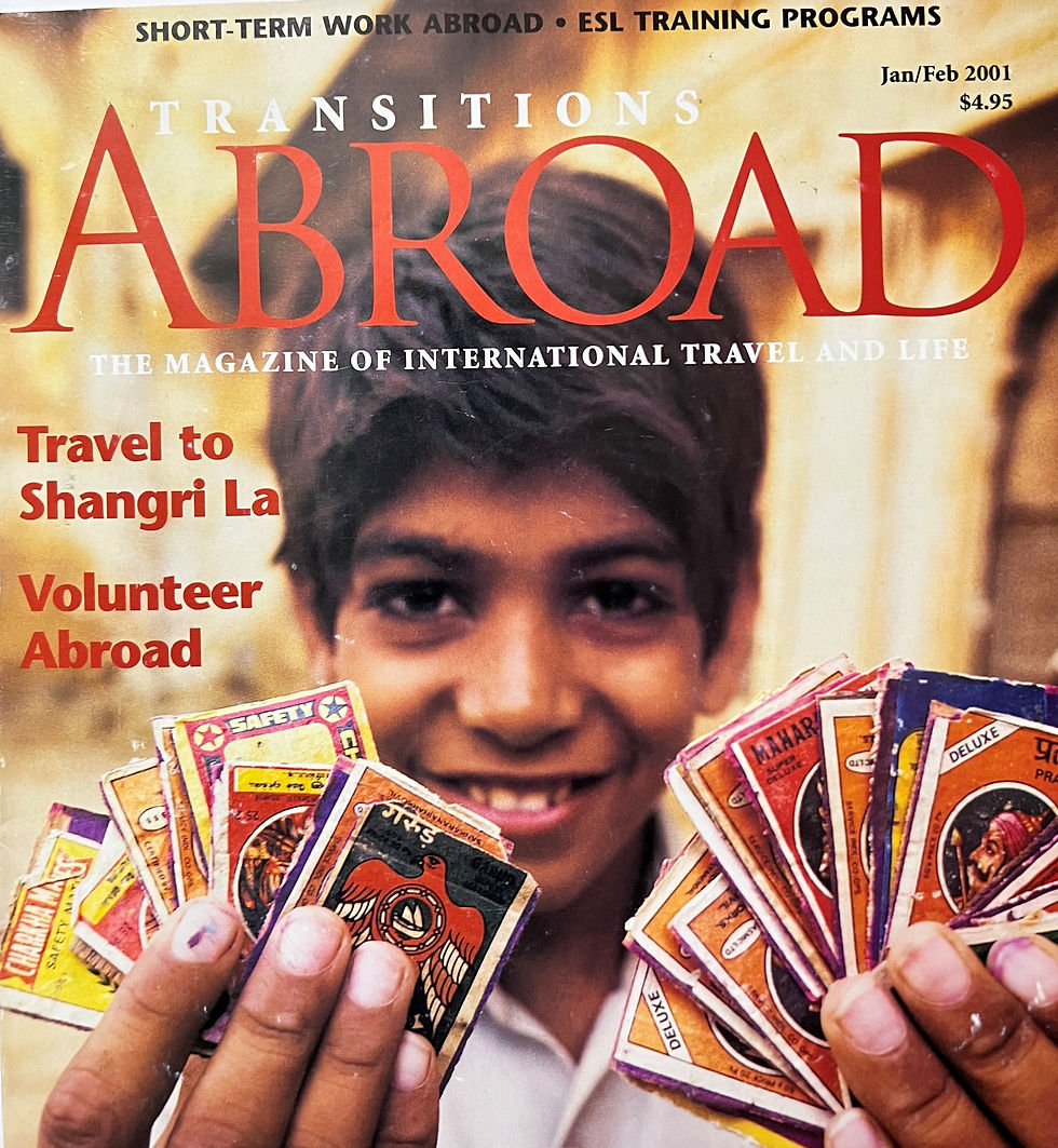 Cover of Transitions Abroad Magazine showing a smiling boy holding colorful matchbox labels, representing international travel stories including the article on ecotourism in a Bhutan village.