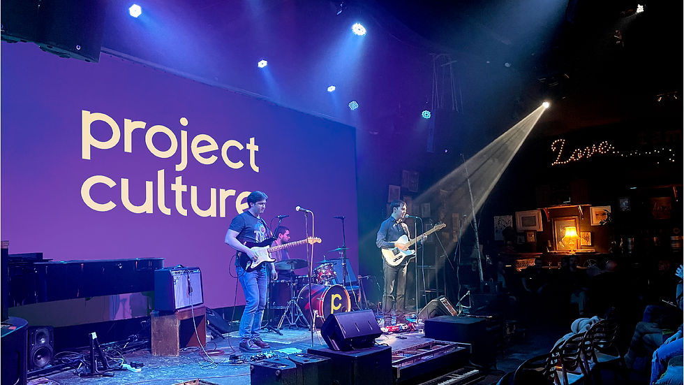 Backdrop: "Project Culture" displayed on a projector screen, with the band performing on stage.