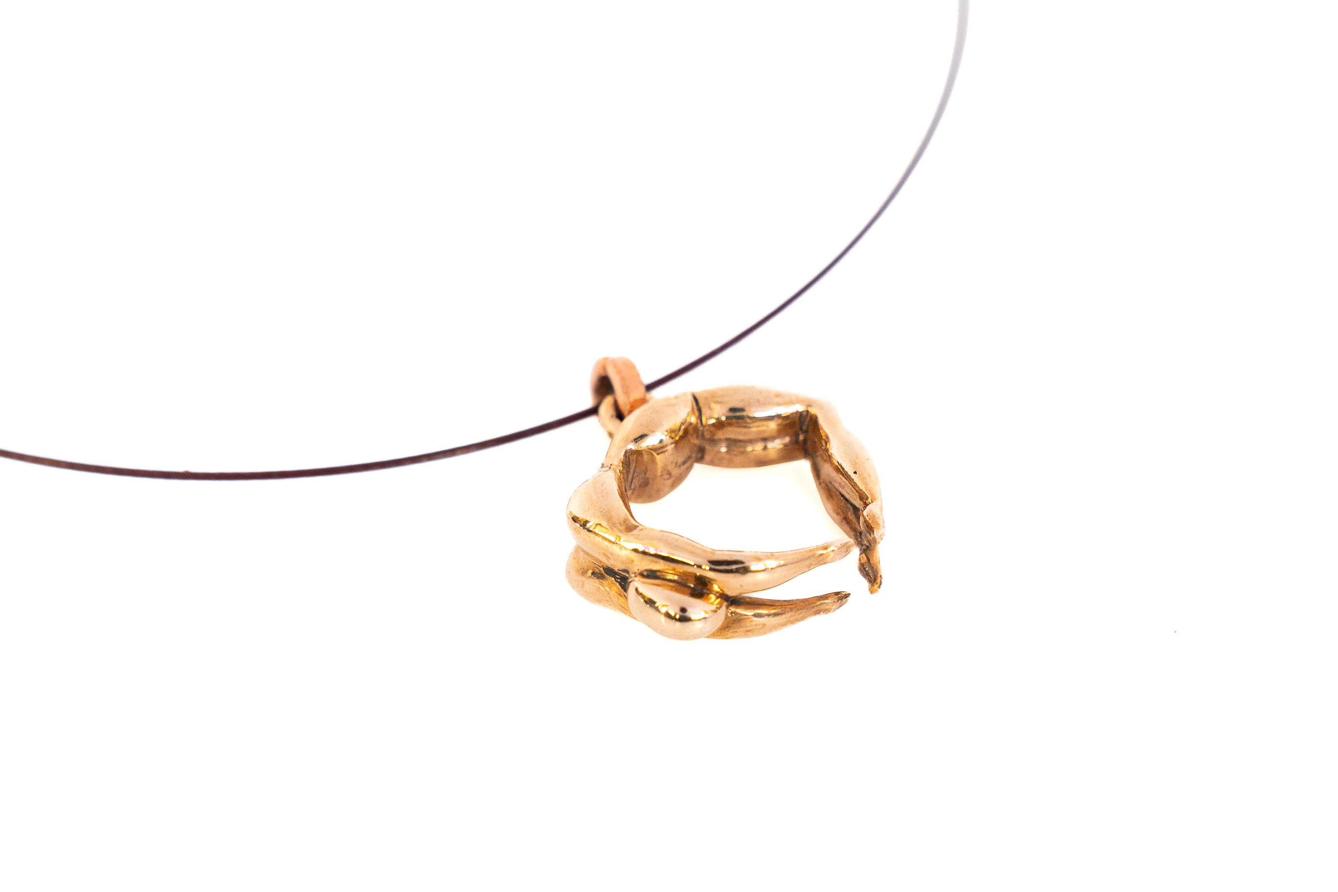 Embrace necklace by Rawa, a bronze pendant of two intertwined forms, shown close-up on a thin cord