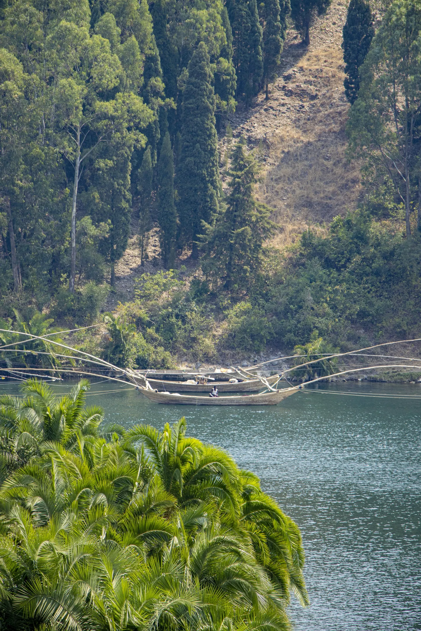 Fishing boats on a calm lake below wooded hills