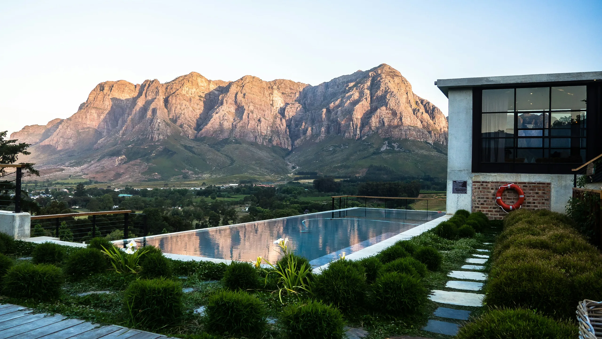 Infinity pool and garden beneath dramatic mountains
