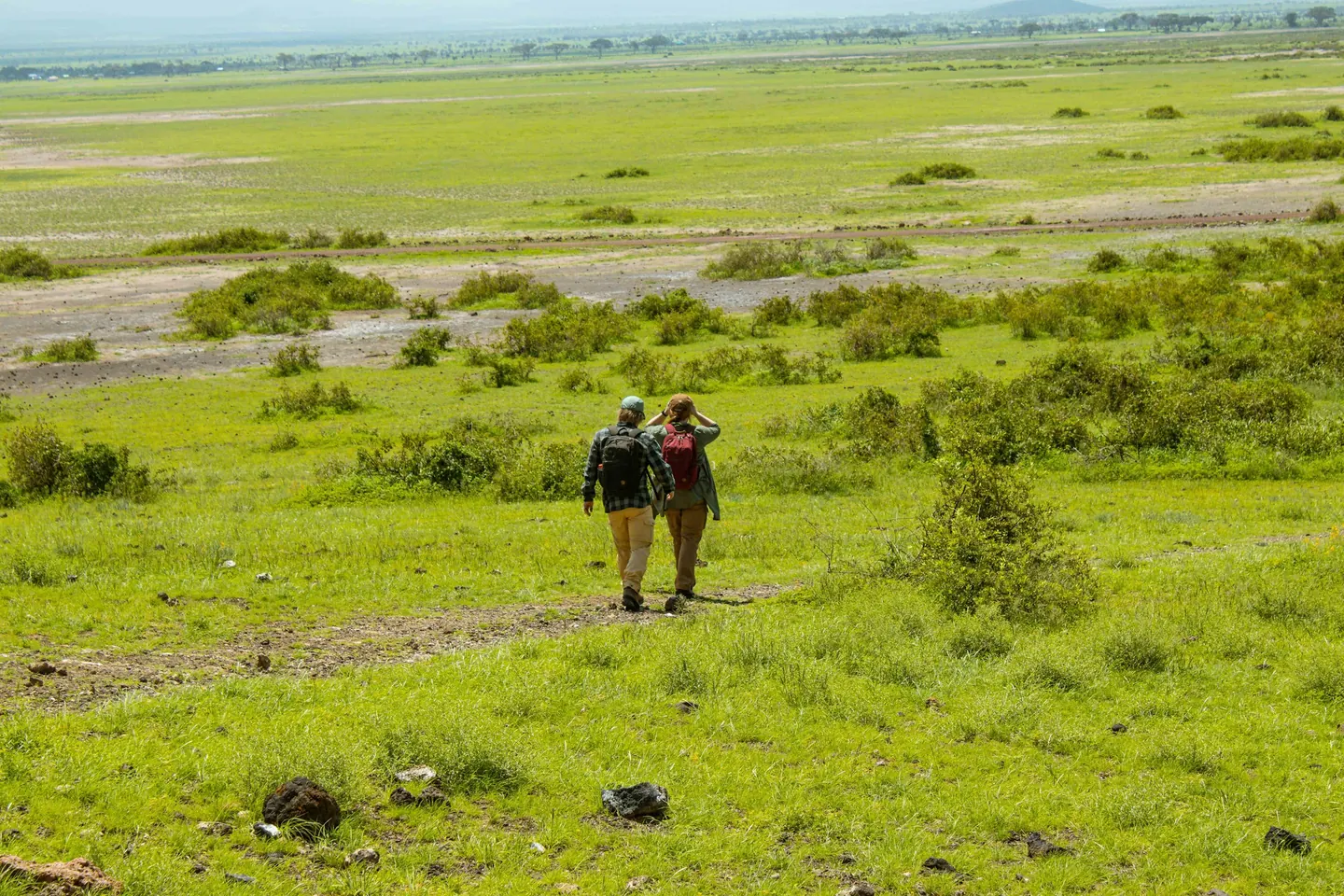Two people walking across open green grassland