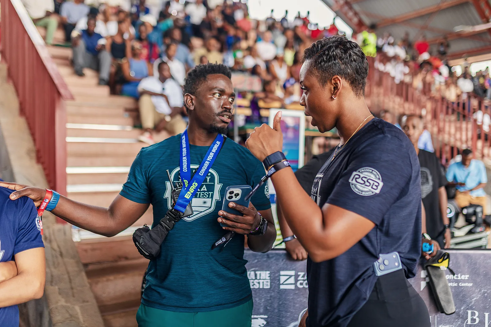 Two event organisers coordinating beside a packed spectator stand