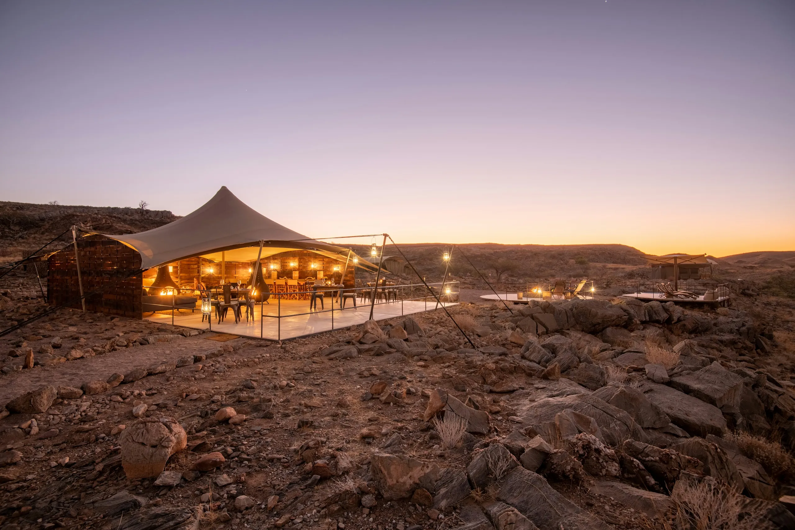 Lantern-lit tented camp in the desert at dusk