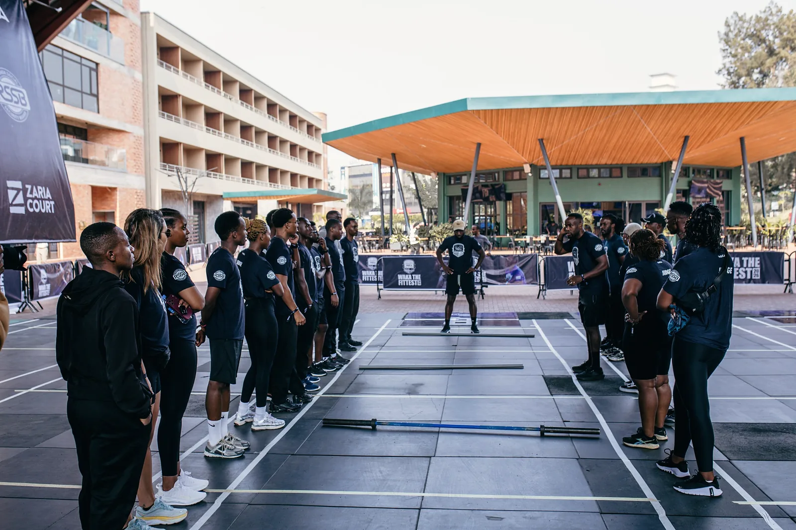 Judges lined up either side of competition lanes with a barbell set out on the floor