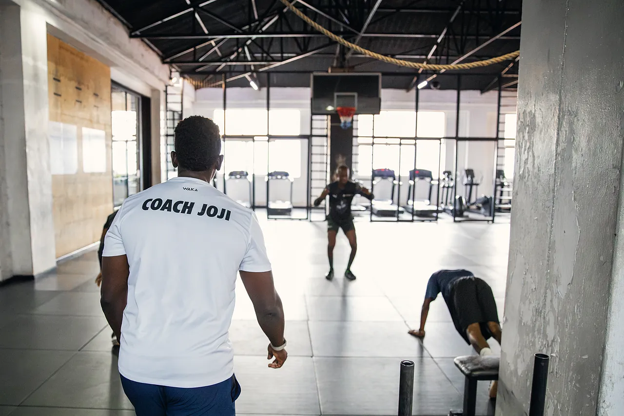 Coach Joji watching two clients train on the gym floor