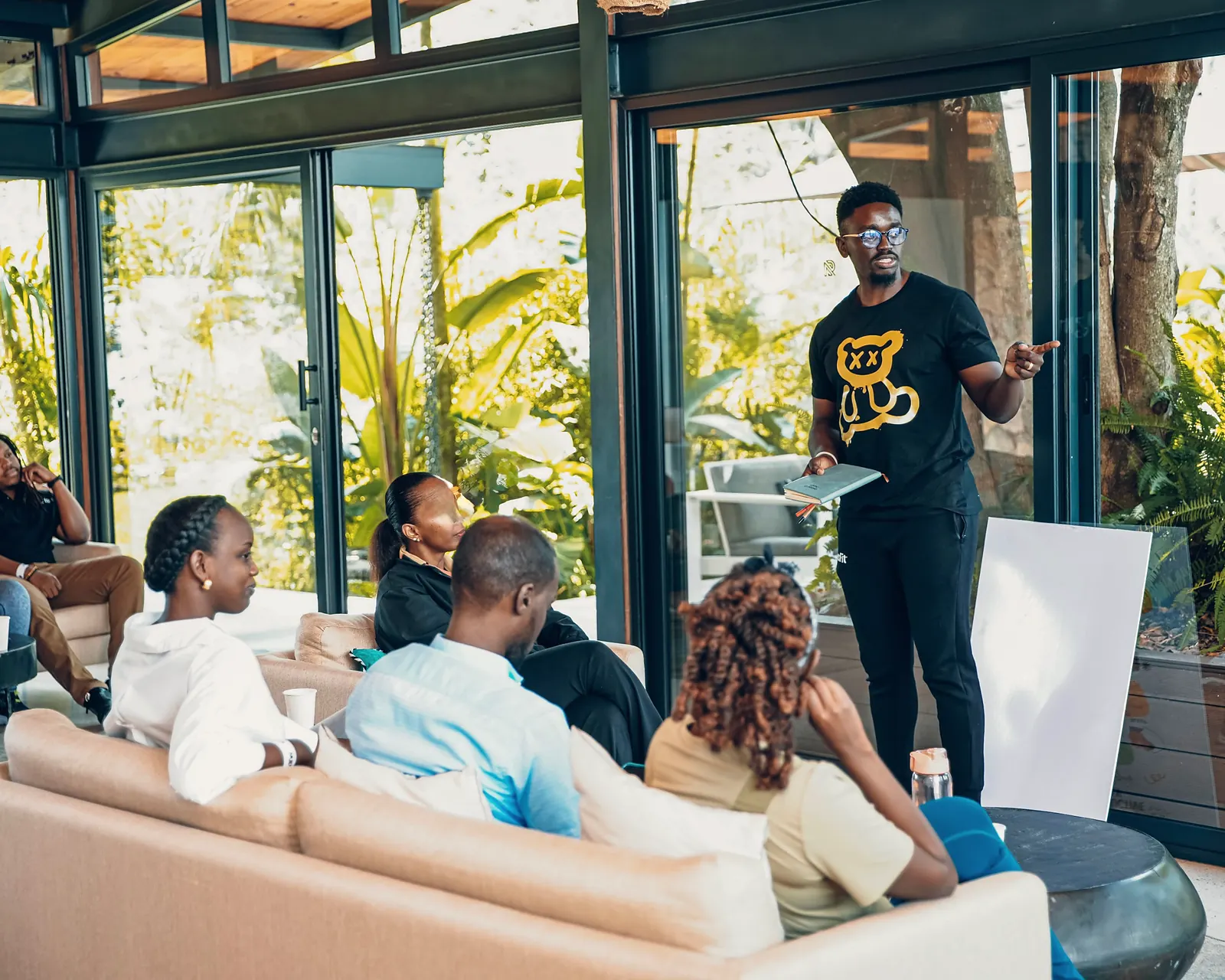 Coach talking with a small group seated on sofas in a bright garden room