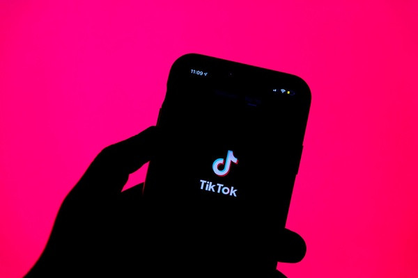 The tik tok logo on a phone with a pink background