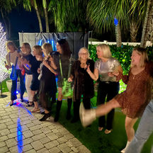 Guests dancing and singing along to karaoke on a professional monitor during a backyard celebration.