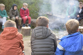 Adults smiling around a campfire.