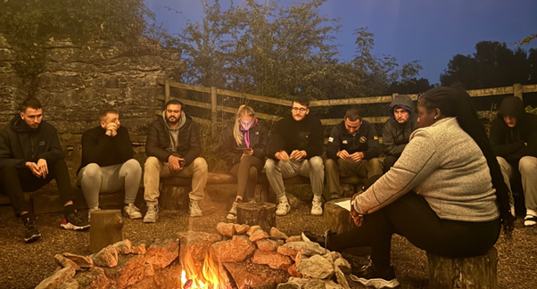 A group of young adults around a campfire at night