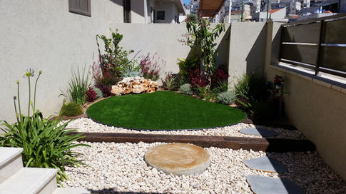 פינת ירק לבית עשוייה דשא, צמחייה, סלעייה וחצץ.