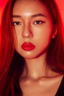 Asian woman with big lips photographed for a fashion shoot wearing red lipstick with gel lighting