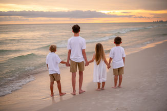 Family hugging in front of pastel skies over the Gulf of Mexico at golden hour