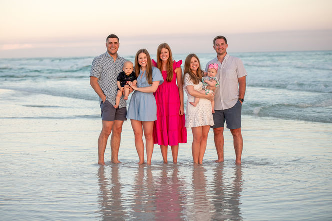 Family hugging in front of pastel skies over the Gulf of Mexico at golden hour