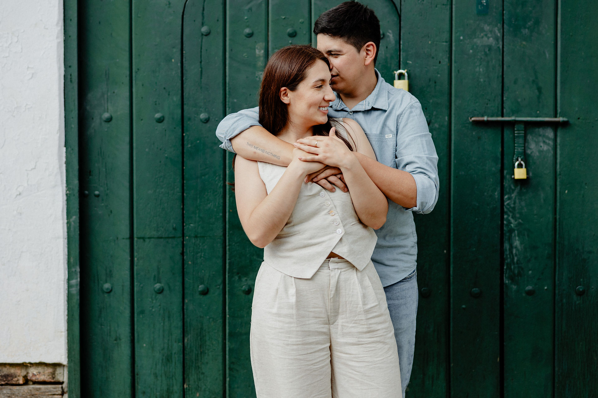 Pareja abrazada junto a sus dos mascotas en los pozos azules de villa de leyva durante una sesion preboda, con cielo nublaco y un paisaje natural como fondo