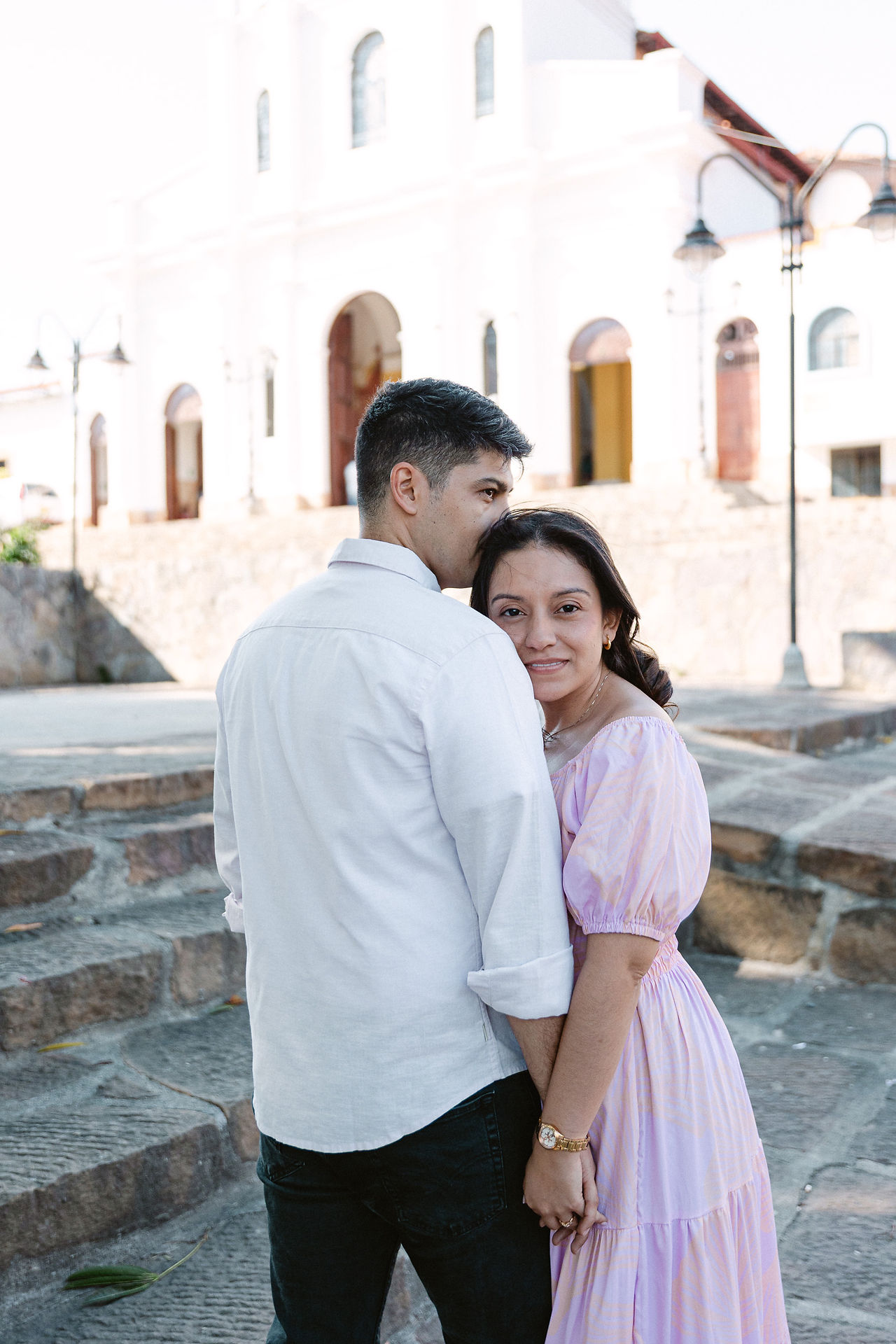 Pareja abrazándose durante su sesión de preboda en Mesa de los Santos, Bucaramanga. Ambos visten camisas blancas mientras se miran con ternura bajo un árbol iluminado por la luz suave del atardecer. Fotografía natural y emotiva capturada por Johan Rey, fotógrafo de bodas en Colombia.